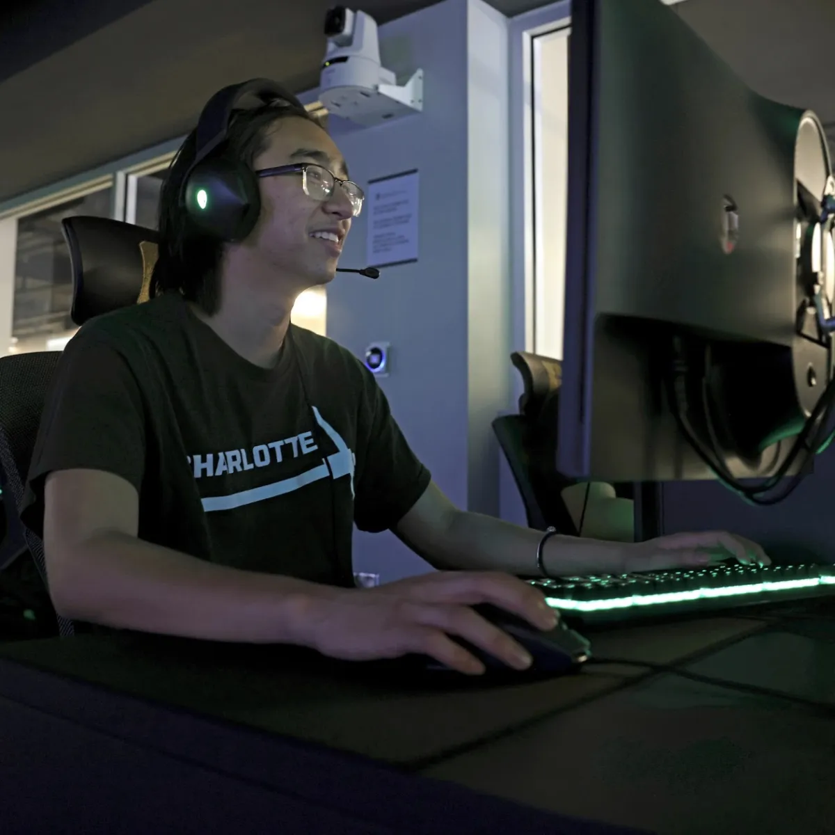 A student in the Esports Arena smiling while playing a computer game